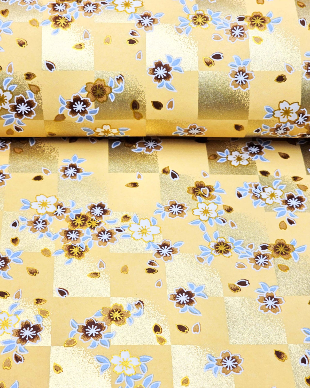 Japanese chiyogami paper featuring brown and white cherry blossoms on a caramel brown and gold ichimatsu (checker) background with metallic gold details.