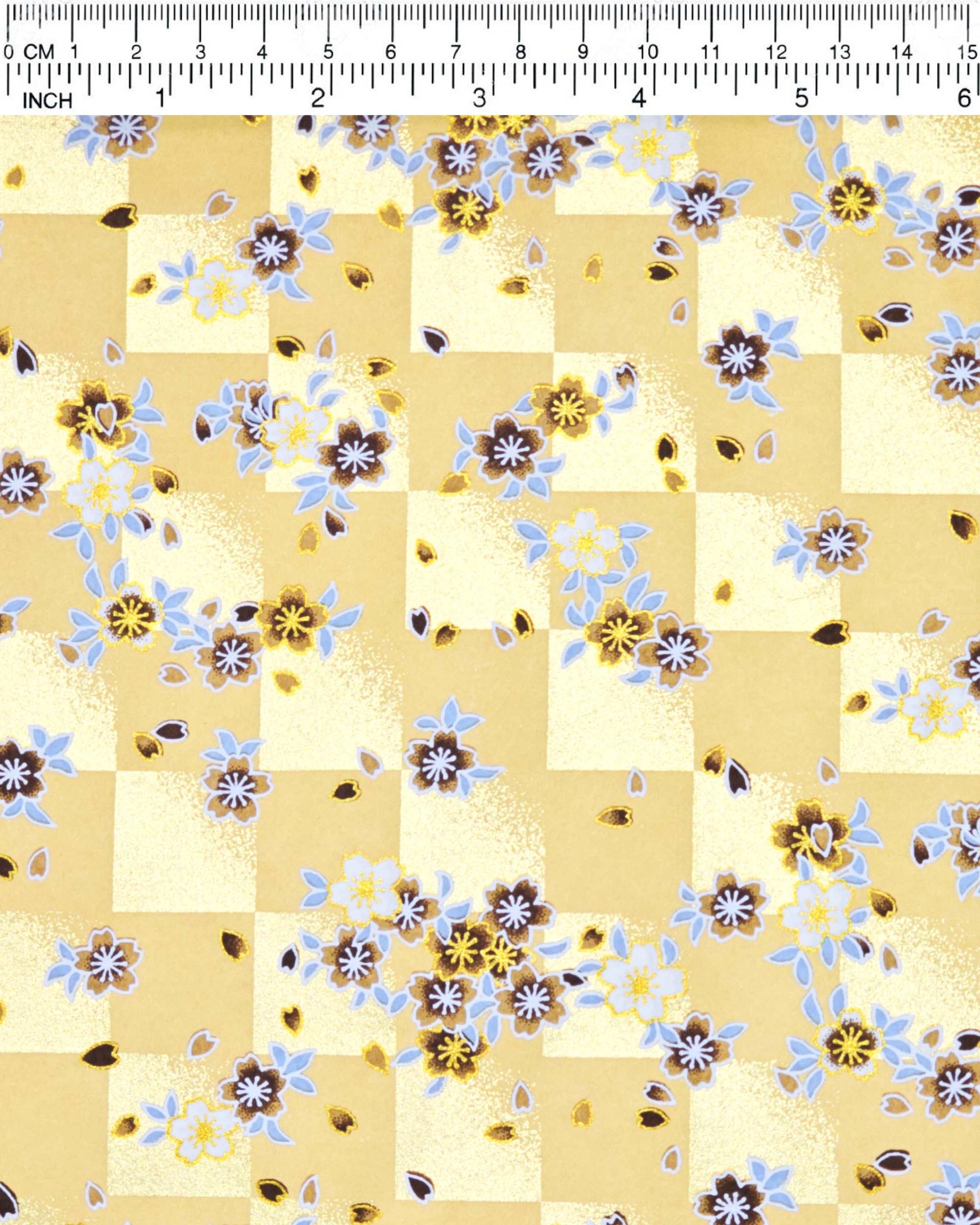 Japanese chiyogami paper featuring brown and white cherry blossoms on a caramel brown and gold ichimatsu (checker) background with metallic gold details.