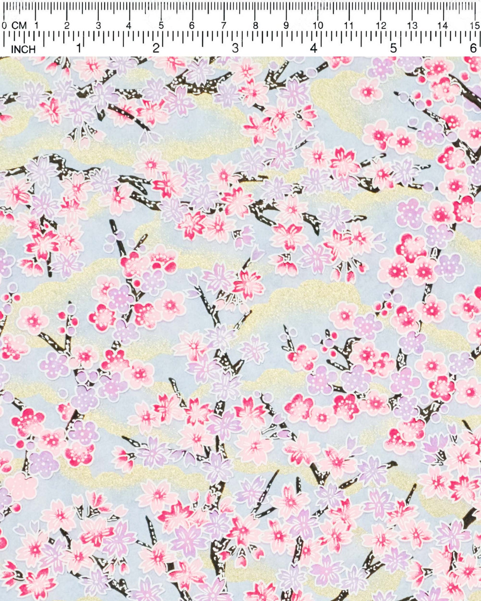 Japanese chiyogami paper featuring light pink and light purple cherry and plum blossoms with black branches on a light blue background with metallic gold details.