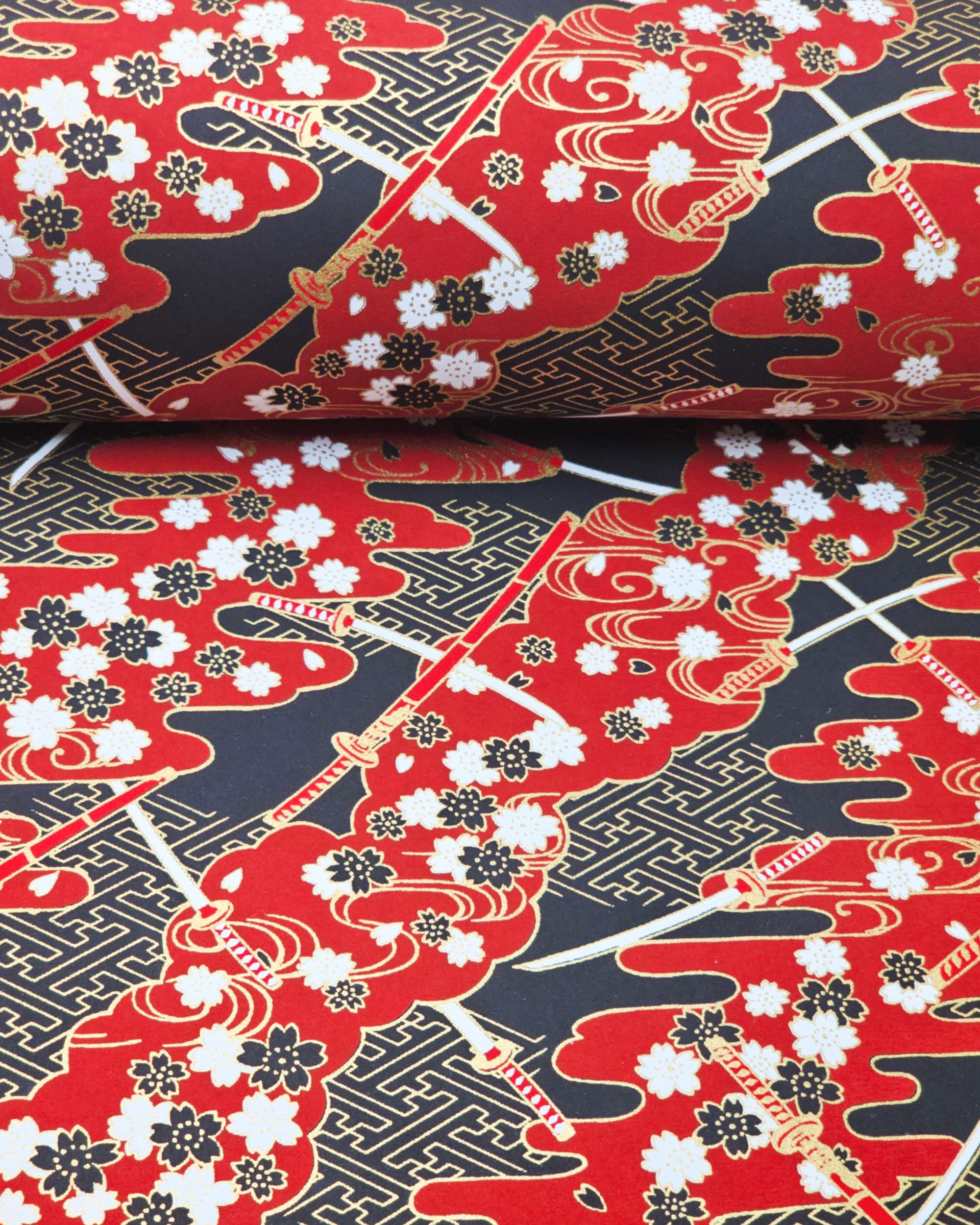 Japanese chiyogami paper featuring red and white katana swords with white and black cherry blossoms on a red and black background with metallic gold details.