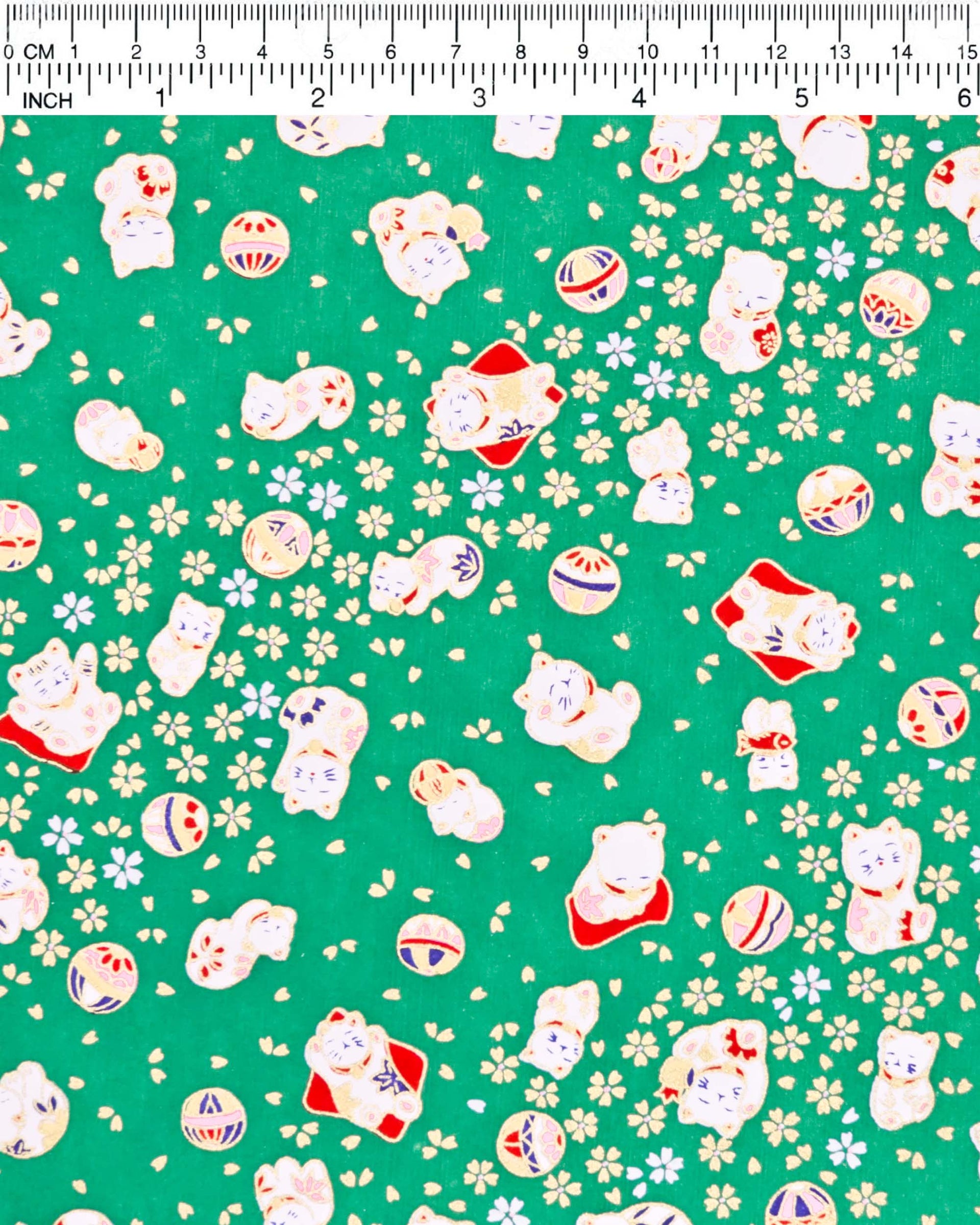 Japanese chiyogami paper featuring assorted white and red Maneki Neko (lucky cats) with small white and gold cherry blossoms and temari balls on a green background with metallic gold details.