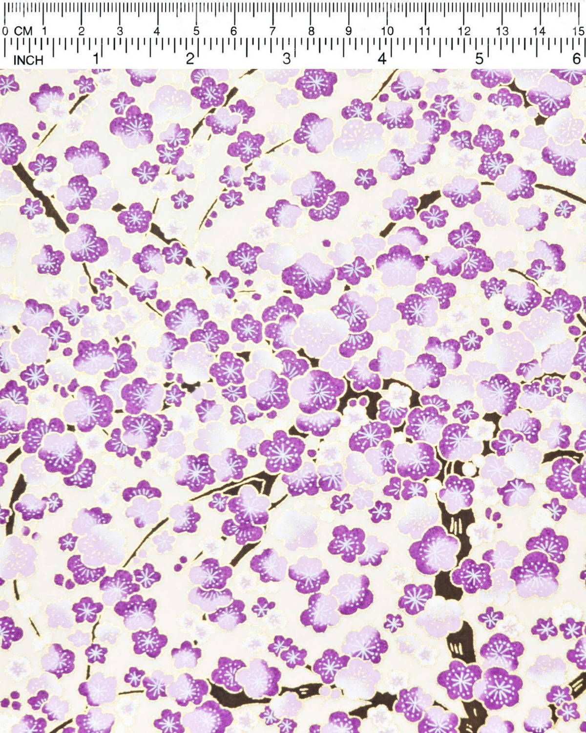 Japanese chiyogami paper featuring purple and white plum blossom trees with brown branches on a cream background with metallic gold details, shown next to a ruler for size reference.