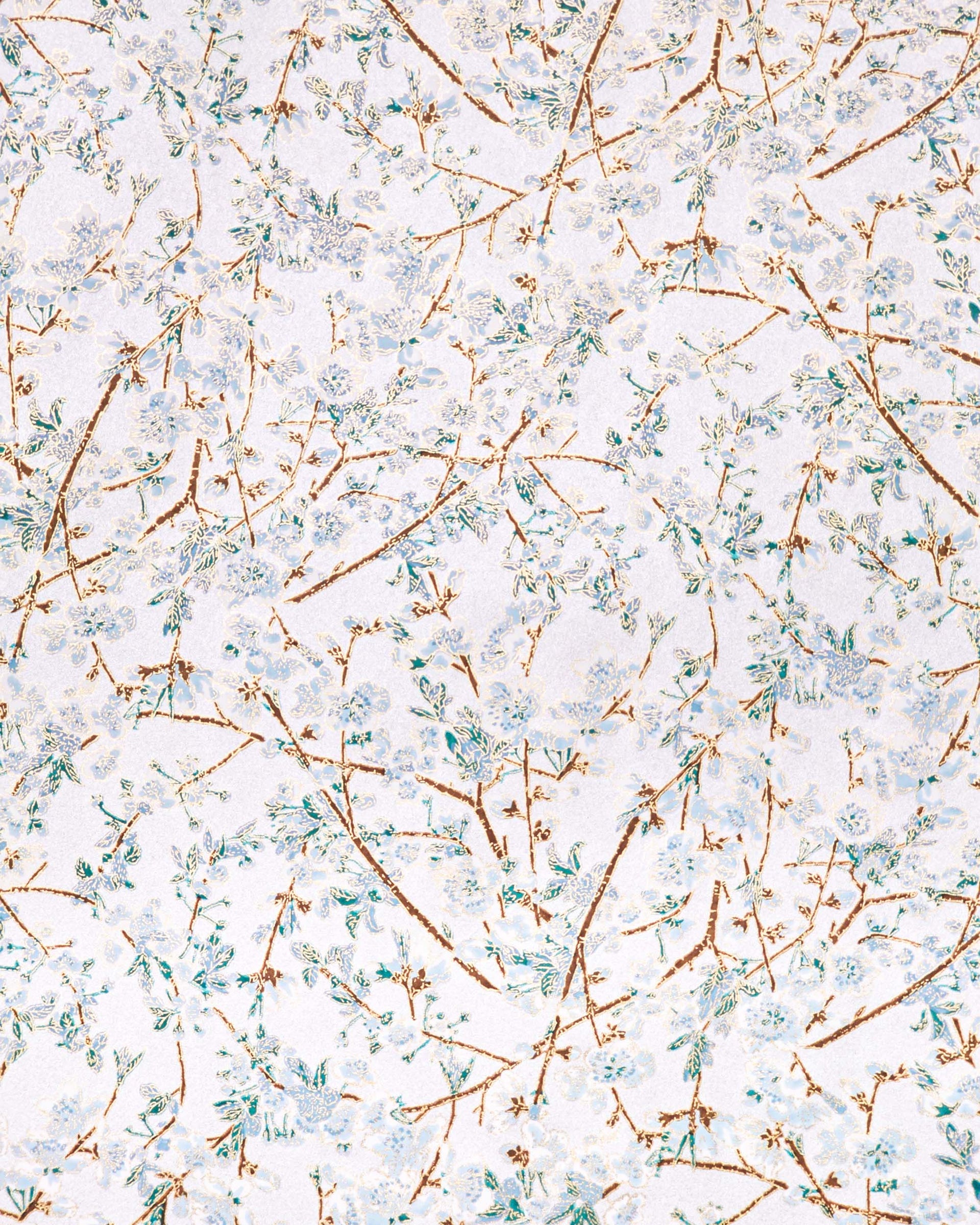 Japanese chiyogami paper featuring light blue and white plum blossoms with dark brown branches and green leaves on a metallic silver background with metallic gold details.
