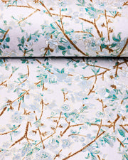 Japanese chiyogami paper featuring light blue and white plum blossoms with dark brown branches and green leaves on a metallic silver background with metallic gold details.
