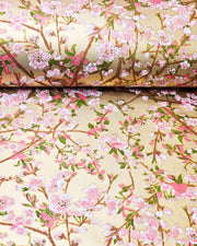Japanese chiyogami paper featuring light pink and white plum blossoms with dark brown branches and green leaves on a gold background with metallic gold details.