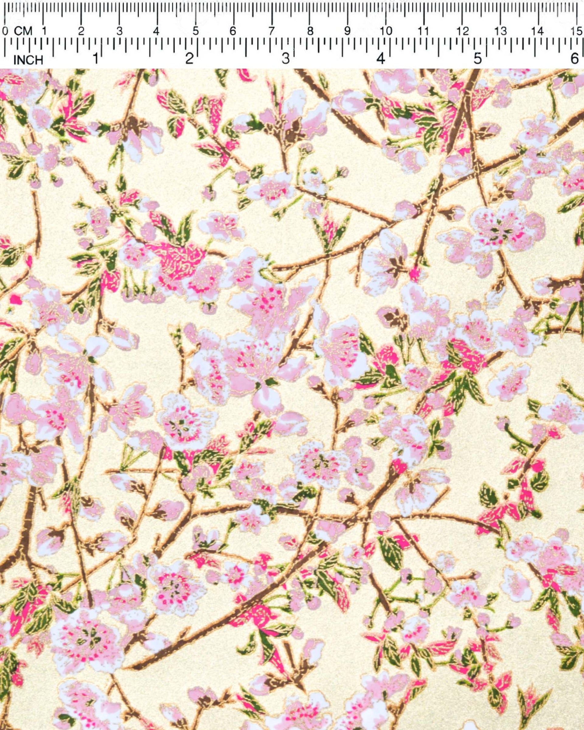 Japanese chiyogami paper featuring light pink and white plum blossoms with dark brown branches and green leaves on a gold background with metallic gold details.