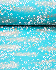 Japanese chiyogami paper featuring small white and gold cherry blossoms on a turquoise blue background with metallic gold details.