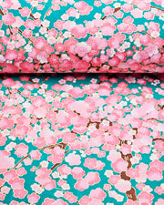 Japanese chiyogami paper featuring pink and white plum blossom trees with brown branches on a teal green background with metallic gold details.