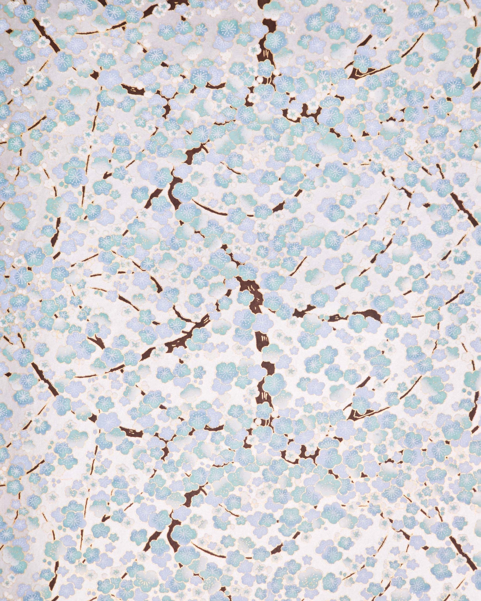 Japanese chiyogami paper featuring light turquoise and white plum blossom trees with brown branches on a silver background with metallic gold details.