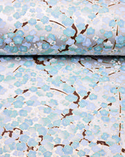 Japanese chiyogami paper featuring light turquoise and white plum blossom trees with brown branches on a silver background with metallic gold details.