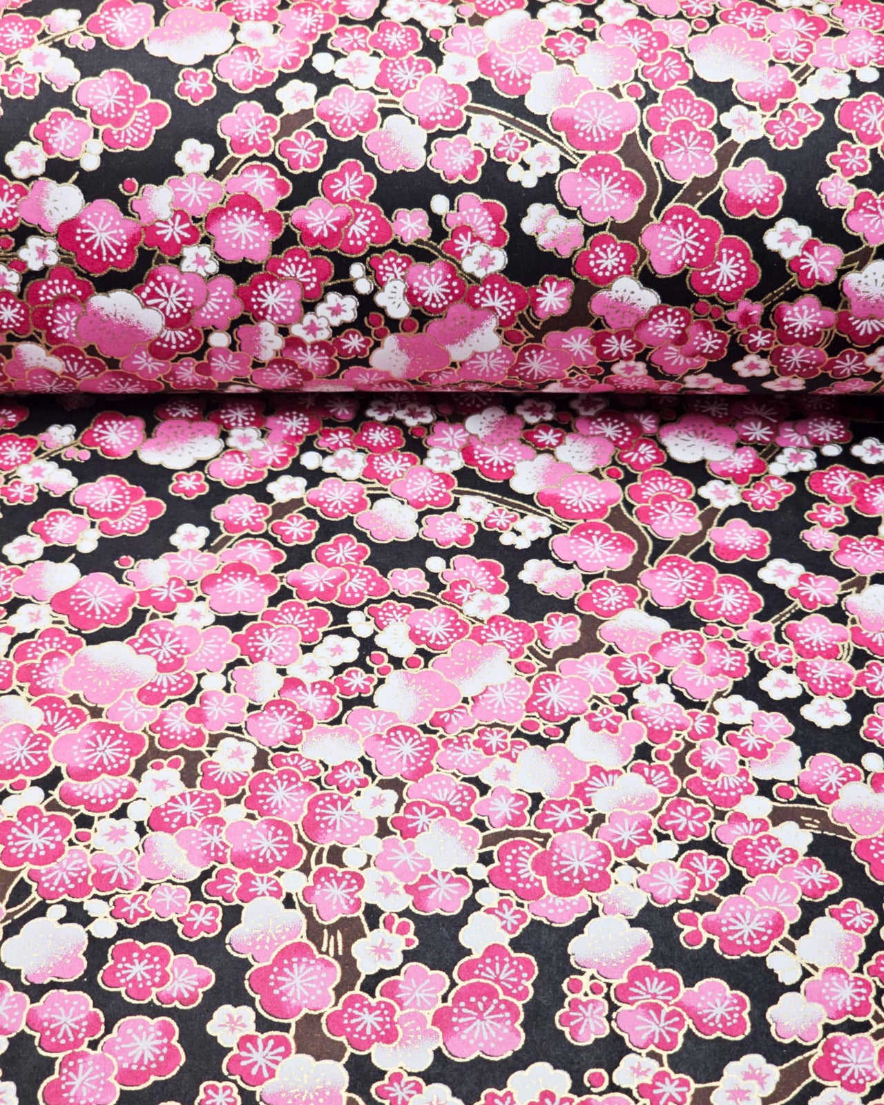 Japanese chiyogami paper featuring pink and white plum blossom trees with brown branches on a black background with metallic gold details.