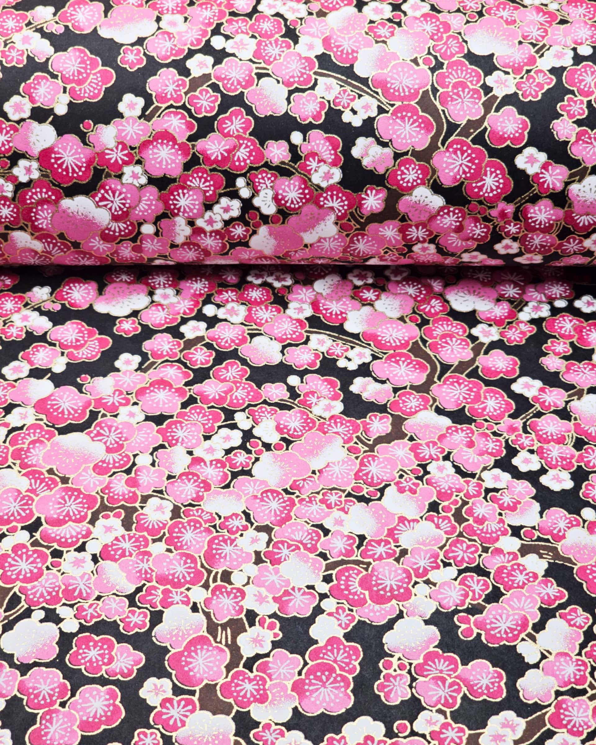 Japanese chiyogami paper featuring pink and white plum blossom trees with brown branches on a black background with metallic gold details.