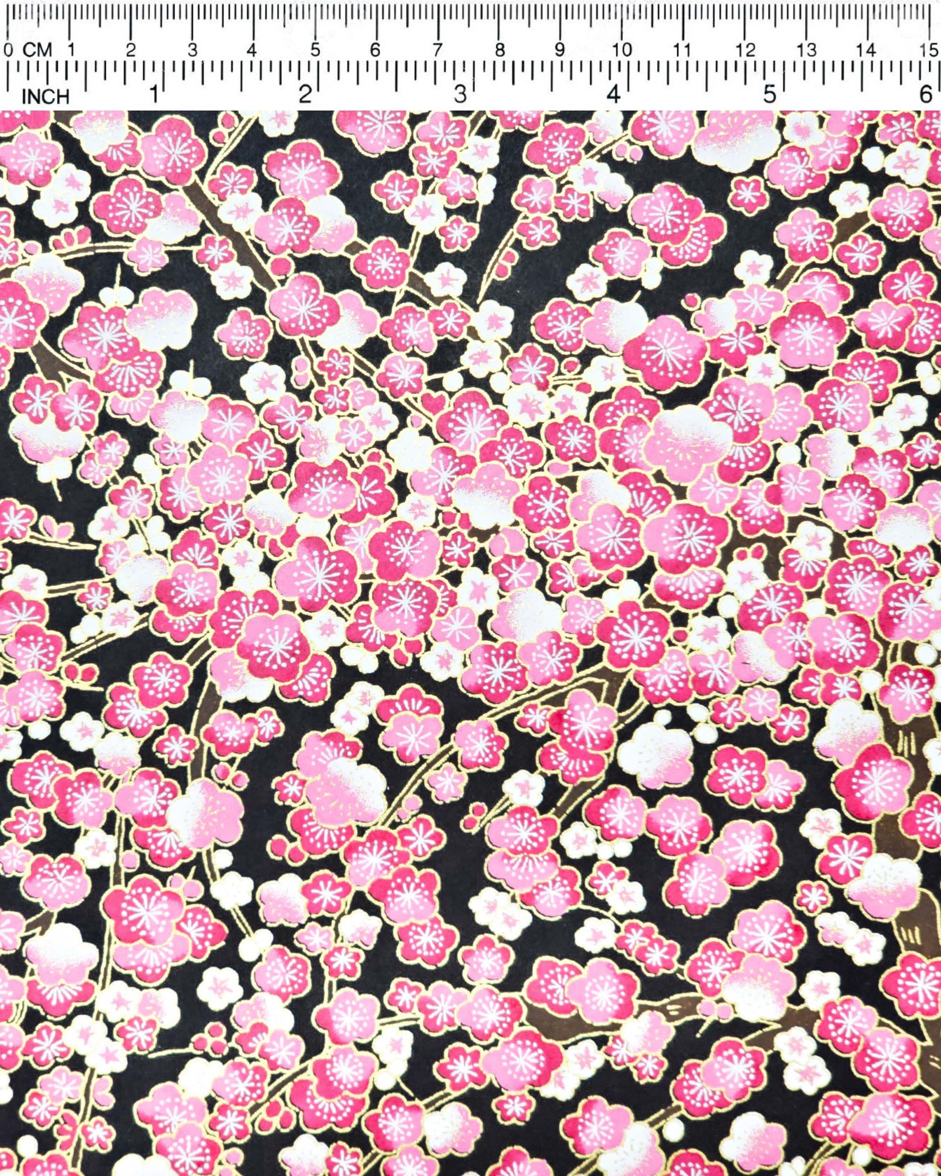 Japanese chiyogami paper featuring pink and white plum blossom trees with brown branches on a black background with metallic gold details.