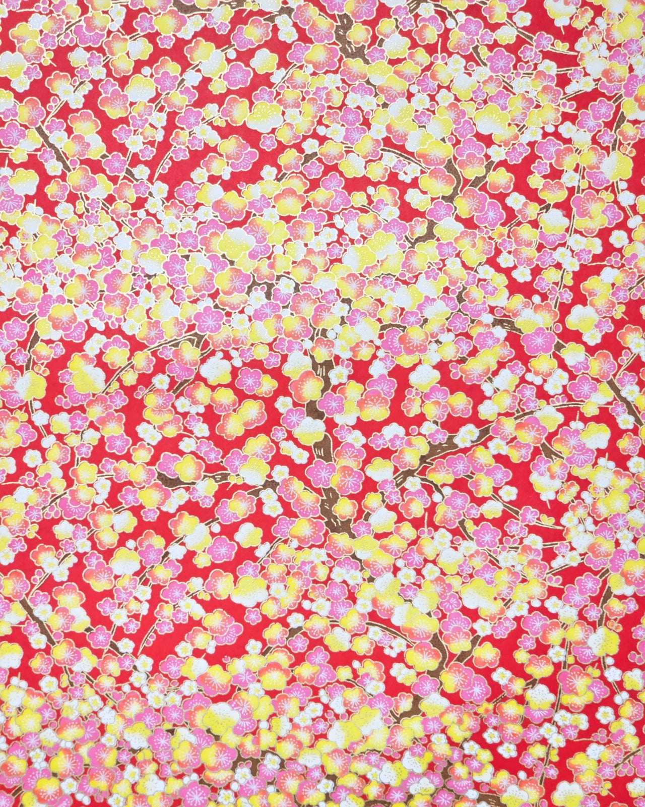 Japanese chiyogami paper featuring pink, yellow, and white plum blossom trees with brown branches on a red background with metallic gold details.