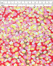 Japanese chiyogami paper featuring pink, yellow, and white plum blossom trees with brown branches on a red background with metallic gold details.