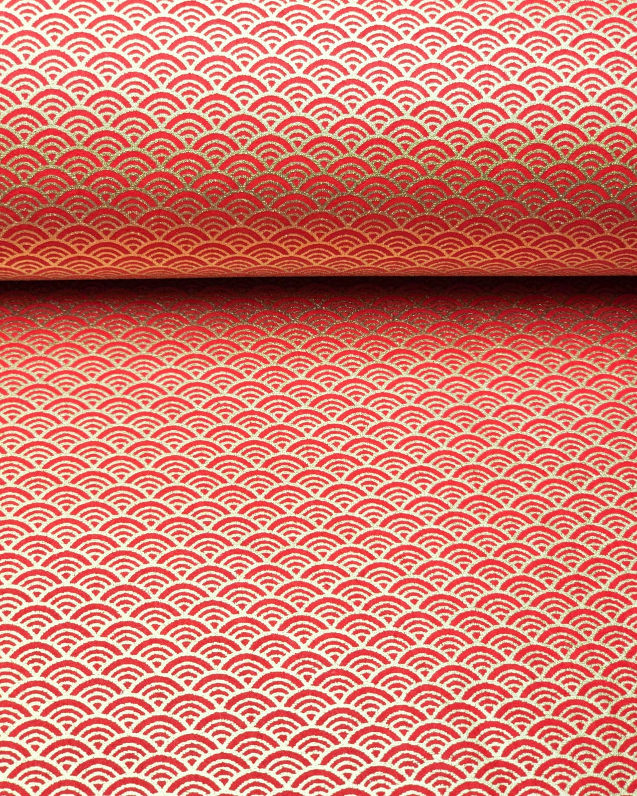 Japanese chiyogami paper featuring a small metallic gold seigaiha wave crest design on a red background.