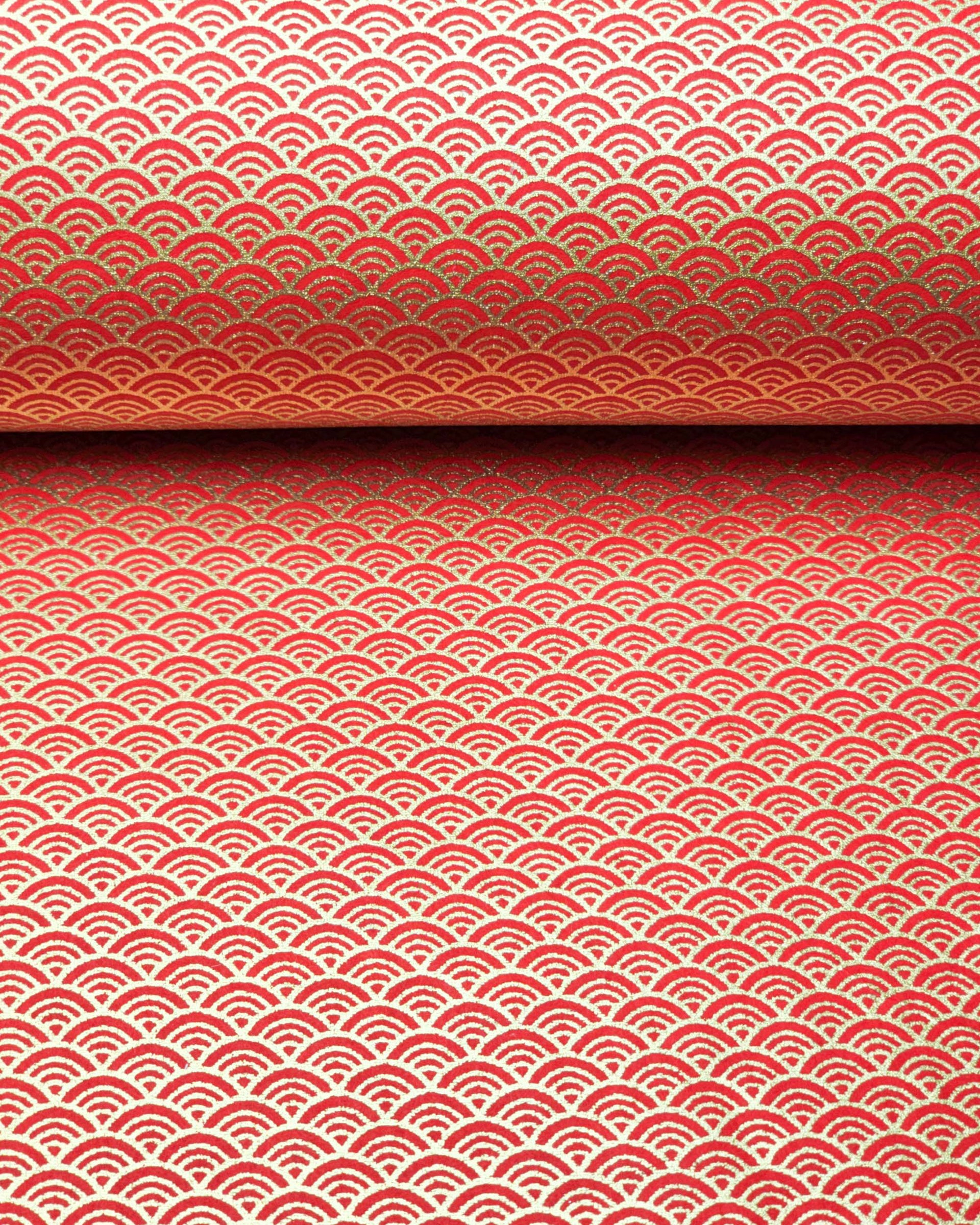 Japanese chiyogami paper featuring a small metallic gold seigaiha wave crest design on a red background.