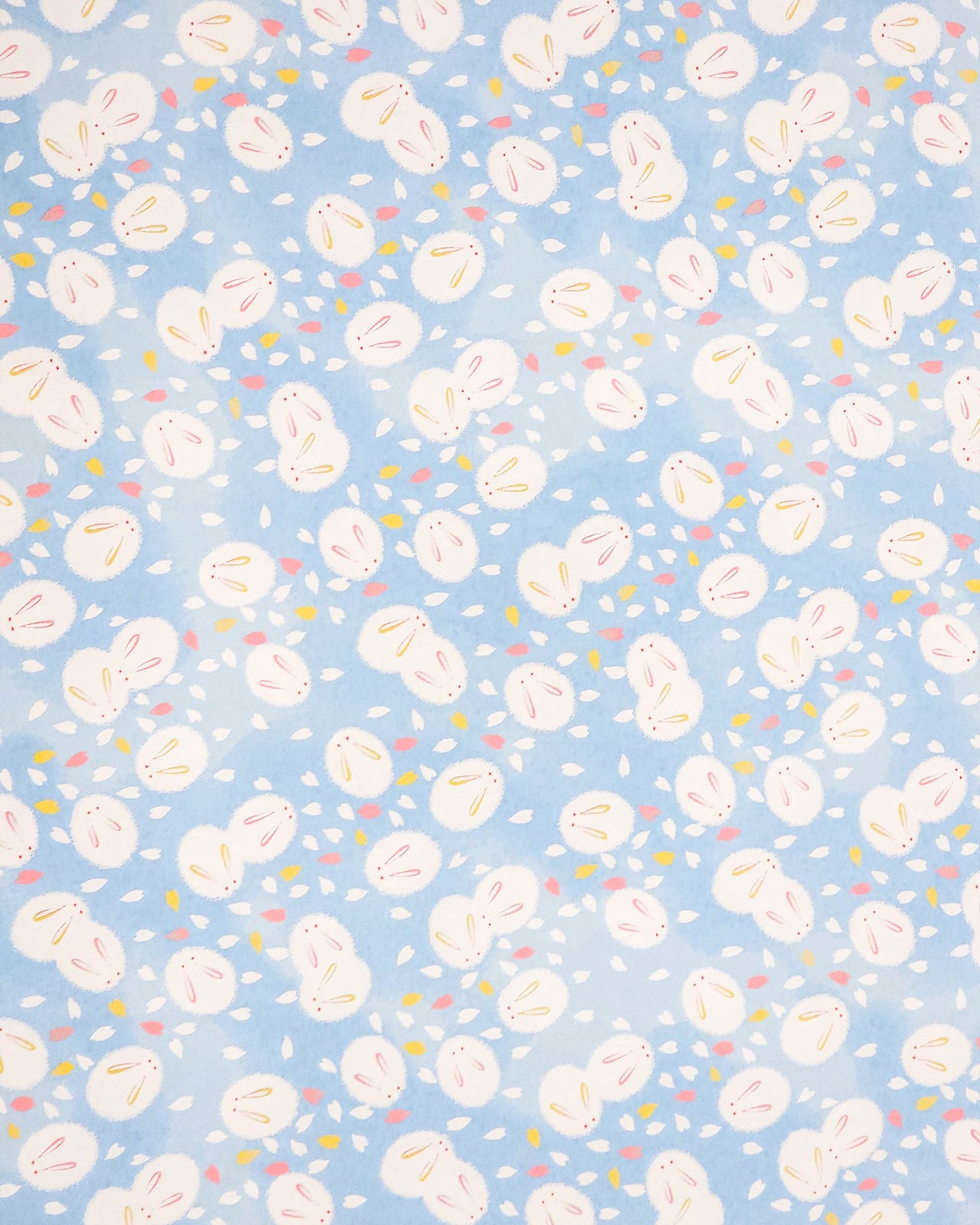Japanese chiyogami paper featuring round white rabbits with pink and yellow ears surrounded by white, pink, and yellow flower petals on light blue background.