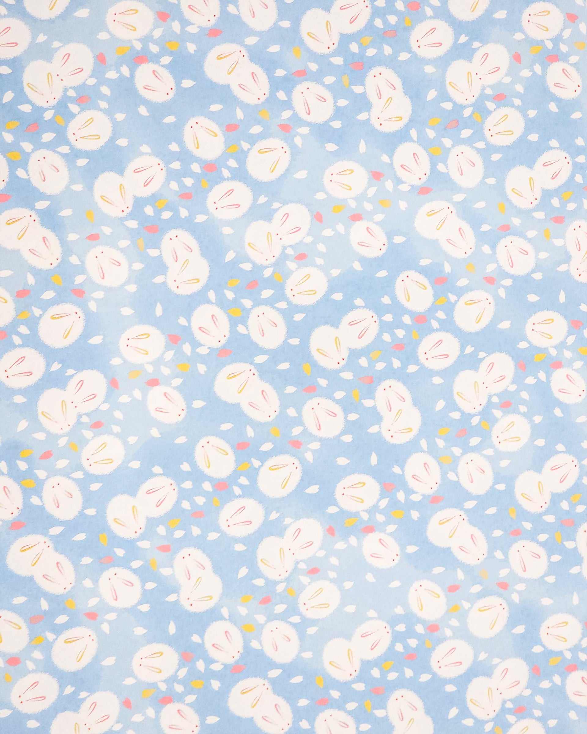 Japanese chiyogami paper featuring round white rabbits with pink and yellow ears surrounded by white, pink, and yellow flower petals on light blue background.