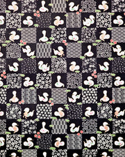 Japanese chiyogami paper featuring white snakes and white assorted traditional Japanese designs in an ichimatsu (checker) design on a black background with metallic gold details. Small red flowers and green leaves accent the design.