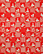 Japanese chiyogami paper featuring white snakes and white assorted traditional Japanese designs in an ichimatsu (checker) design on a red background with metallic gold details. Small pink flowers and green leaves accent the design.