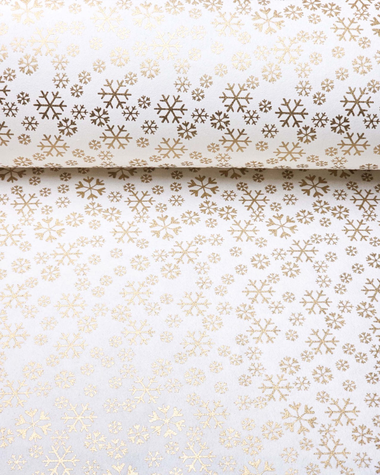 Japanese chiyogami paper featuring metallic gold snowflakes of various sizes on a white background.