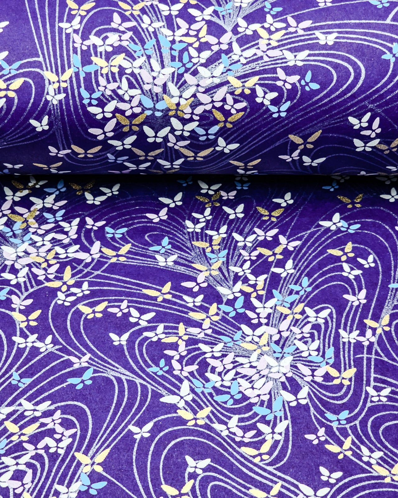 Japanese chiyogami paper featuring small purple, white, blue and metallic gold butterflies on a dark blue background.