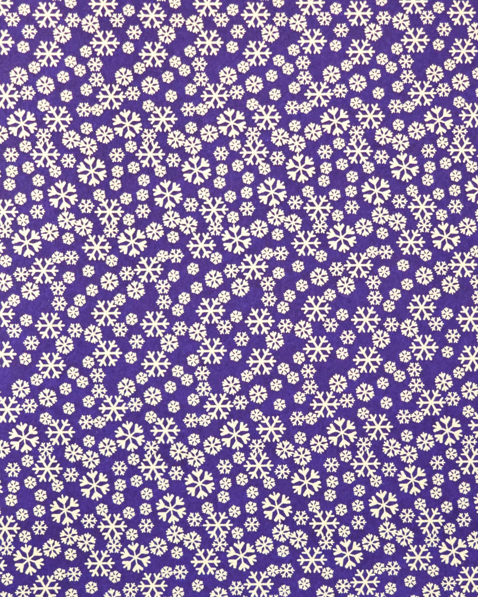 Japanese chiyogami paper featuring metallic gold snowflakes of various sizes on a dark blue background.