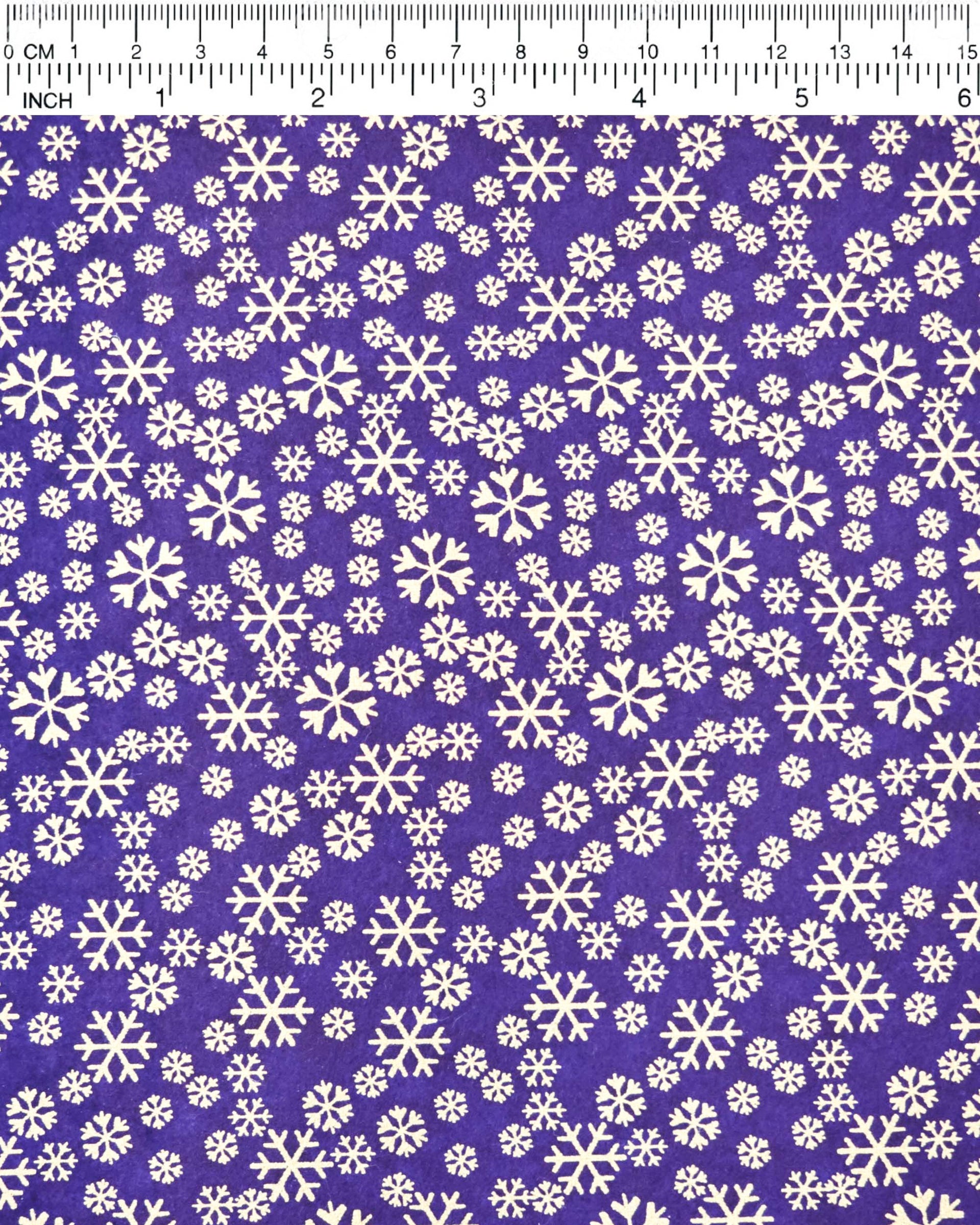 Japanese chiyogami paper featuring metallic gold snowflakes of various sizes on a dark blue background.