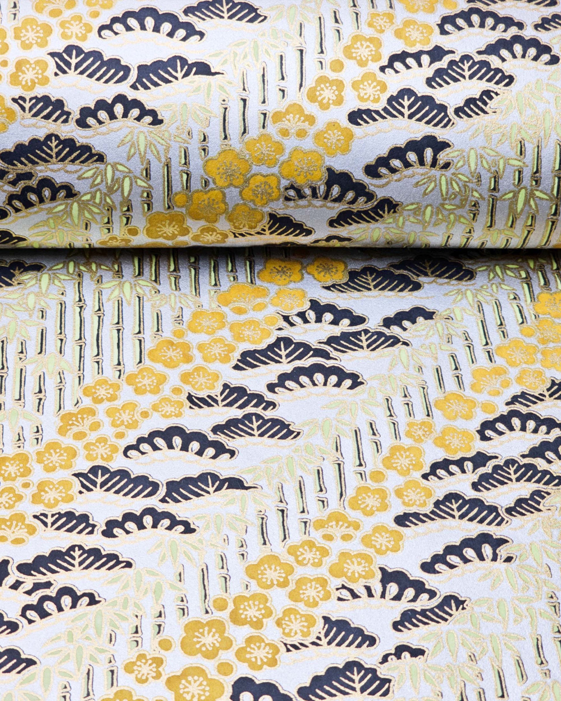 Japanese chiyogami paper featuring orange plum blossoms, black pine, and green bamboo on a metallic silver background with metallic gold details.