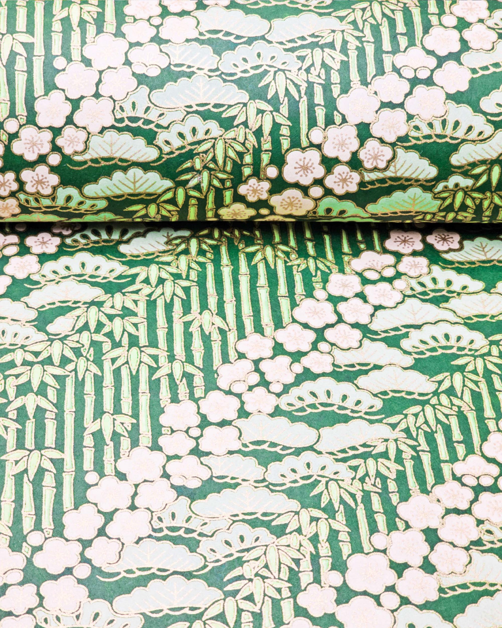 Japanese chiyogami paper featuring cream plum blossoms, light green pine, and green bamboo on green background with metallic gold details.
