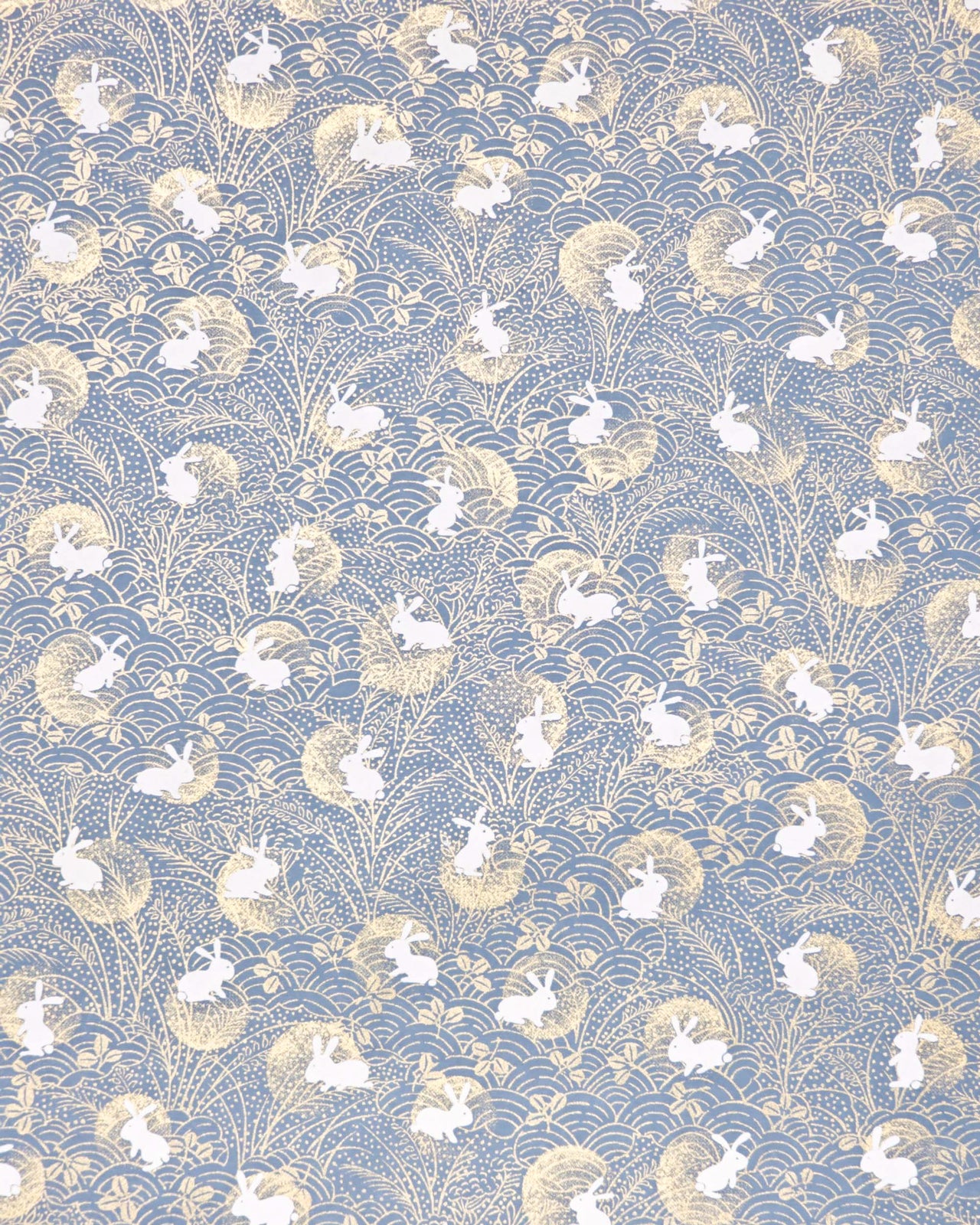Japanese chiyogami paper featuring white rabbits with gold moons on a blue gray background with metallic gold details.