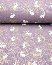 Japanese chiyogami paper featuring white rabbits with gold moons on a purple background with metallic gold details.