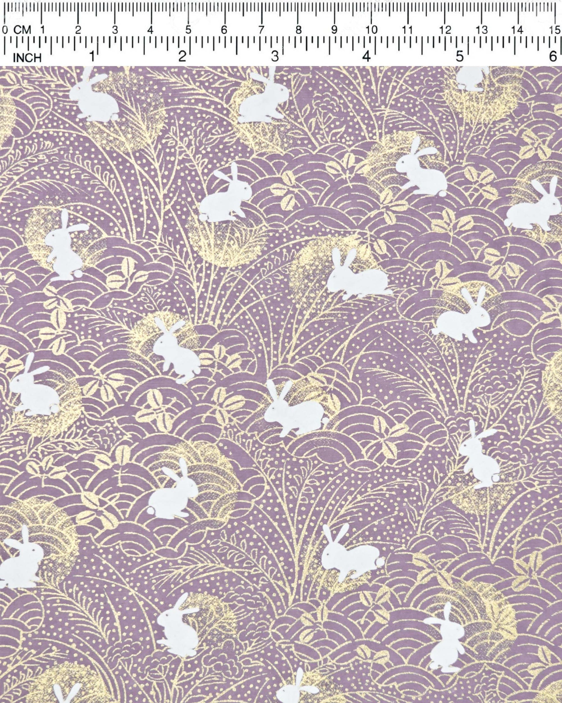 Japanese chiyogami paper featuring white rabbits with gold moons on a purple background with metallic gold details.