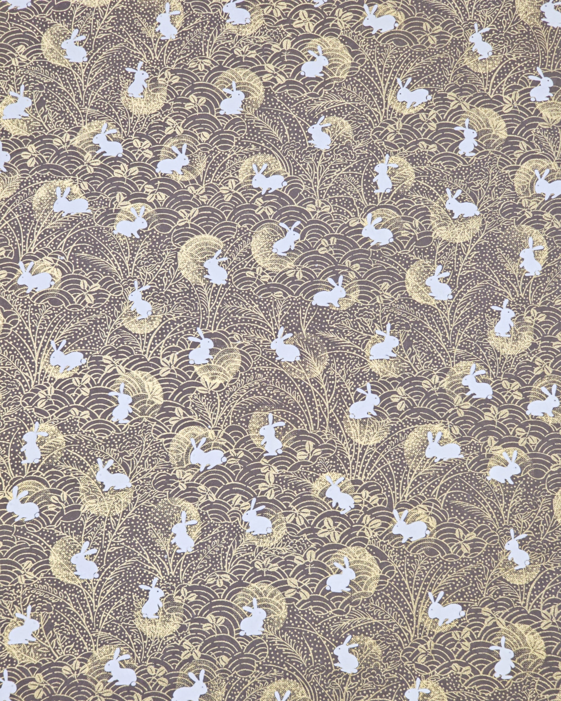 Japanese chiyogami paper featuring white rabbits with gold moons on a brown background with metallic gold details.