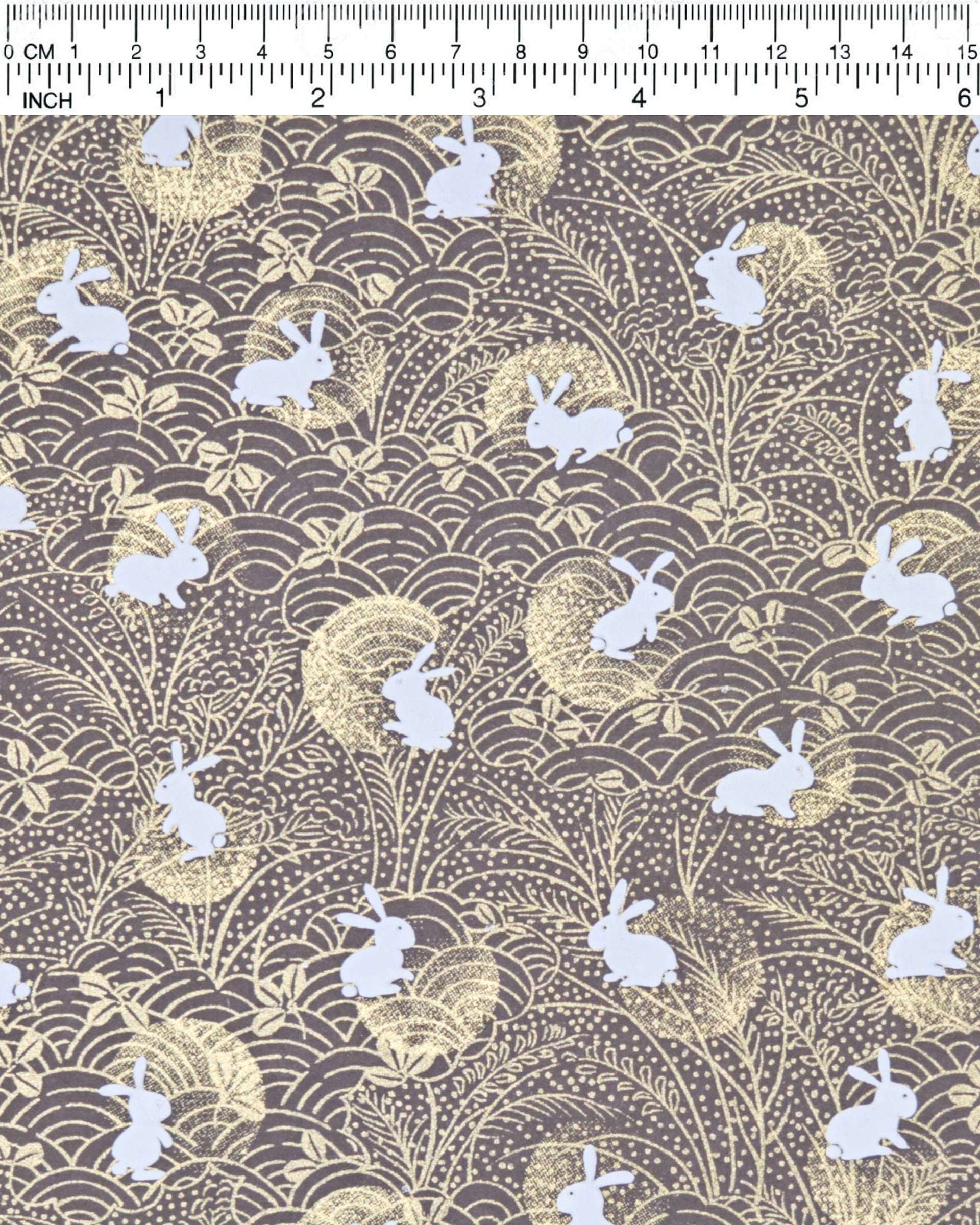 Japanese chiyogami paper featuring white rabbits with gold moons on a brown background with metallic gold details.