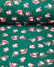Japanese chiyogami paper featuring cartoon Santas in red outfits pulling sleds with presents and carrying sacks of presents on a green background with metallic gold details. 