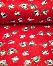 Japanese chiyogami paper featuring cartoon Santas in green outfits pulling sleds with presents and carrying sacks of presents on a red background with metallic gold details. 