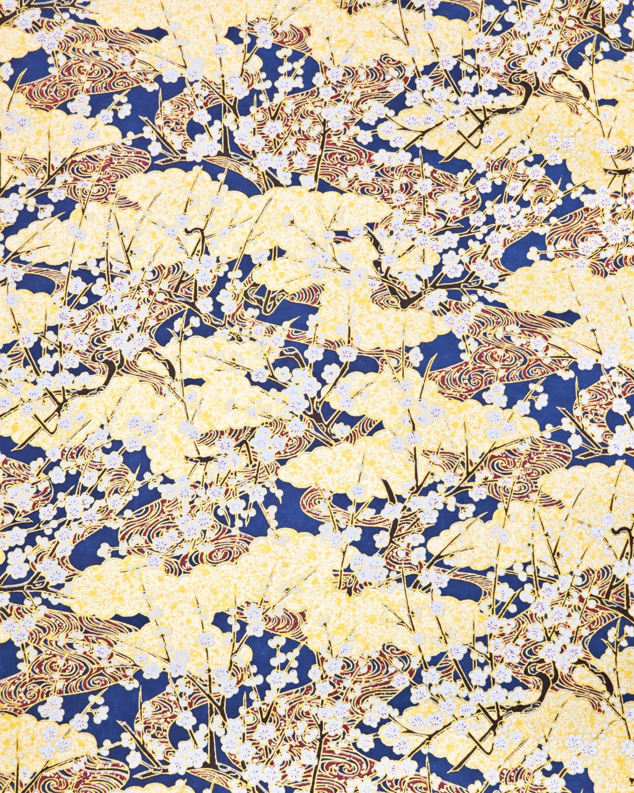Japanese chiyogami paper featuring small white plum blossom branches with red and gold swirls on a dark blue and gold background with metallic gold details.