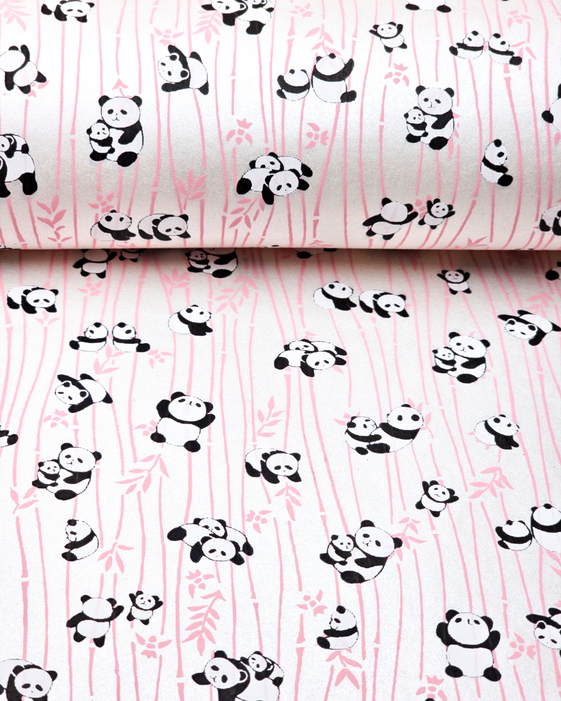Japanese chiyogami paper featuring black and white pandas with pink bamboo stalks on a pearlescent white background.