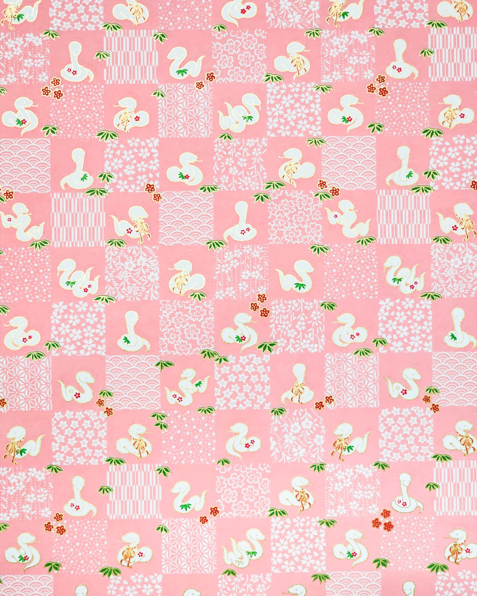 Japanese chiyogami paper featuring white snakes and white assorted traditional Japanese designs in an ichimatsu (checker) design on a pink background with metallic gold details.