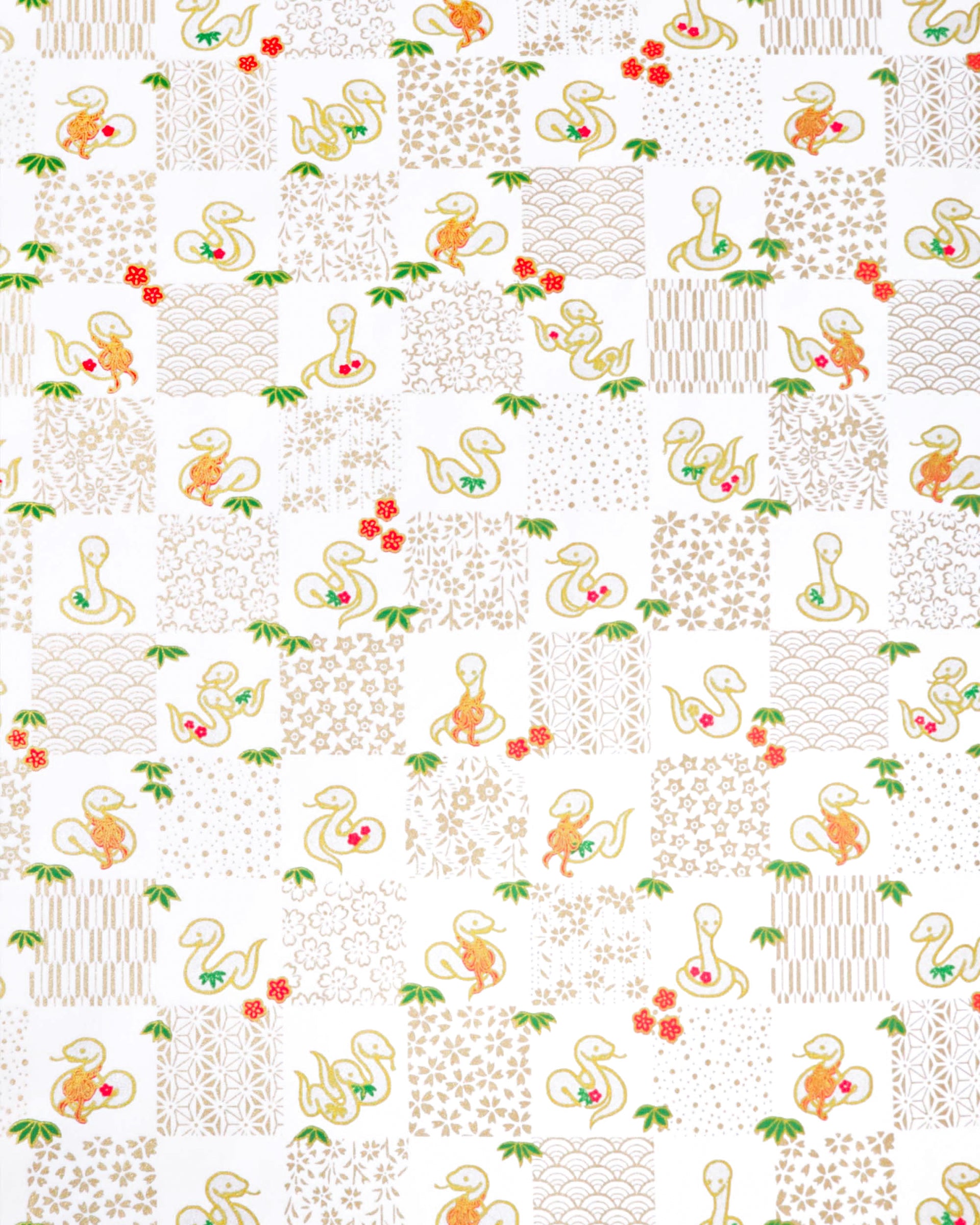 Japanese chiyogami paper featuring silver snakes and gold assorted traditional Japanese designs in an ichimatsu (checker) design on a white background with metallic gold details. Small red plum blossoms and green bamboo leaves are scattered throughout the design.