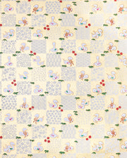 Japanese chiyogami paper featuring white snakes and white assorted traditional Japanese designs in an ichimatsu (checker) design on a gold background with metallic gold details. Small red plum blossoms and green bamboo leaves are scattered throughout the design.