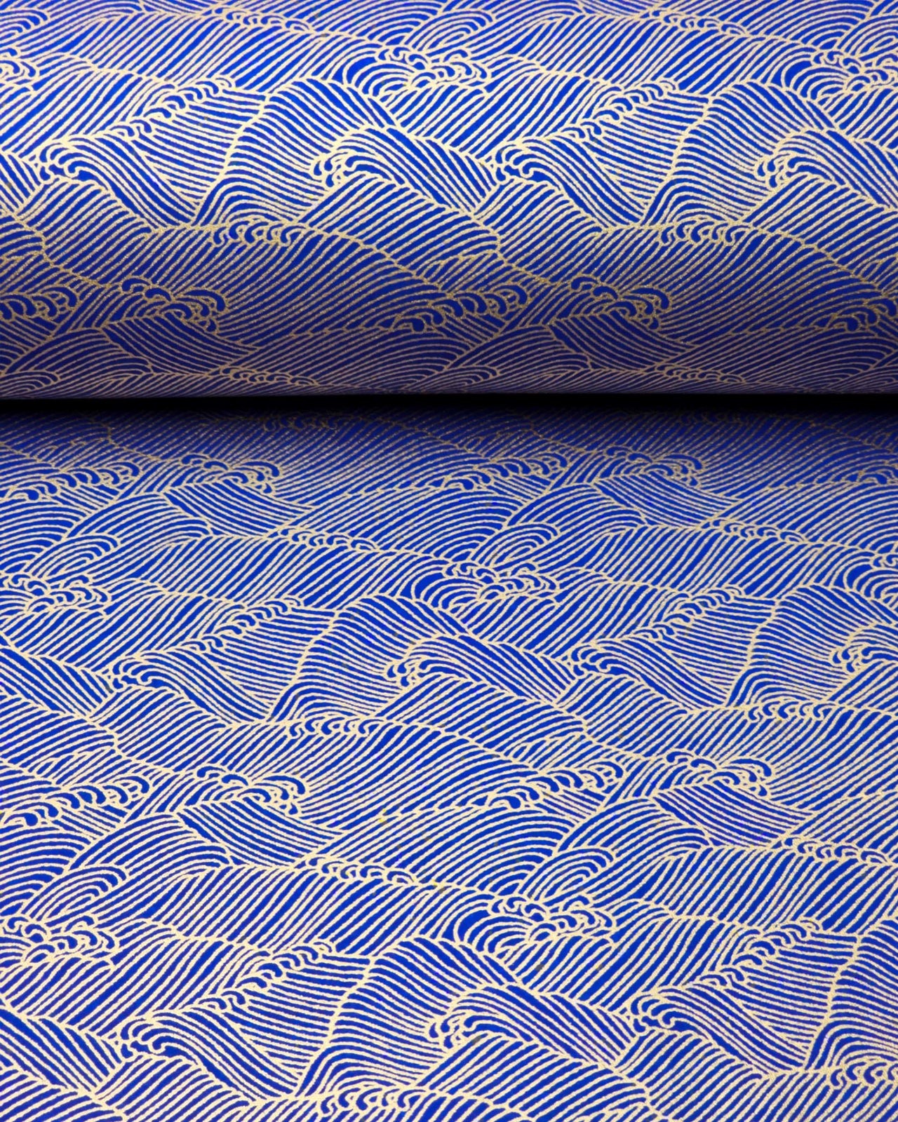 Japanese chiyogami paper featuring small metallic gold waves (aranami) on a dark blue background.