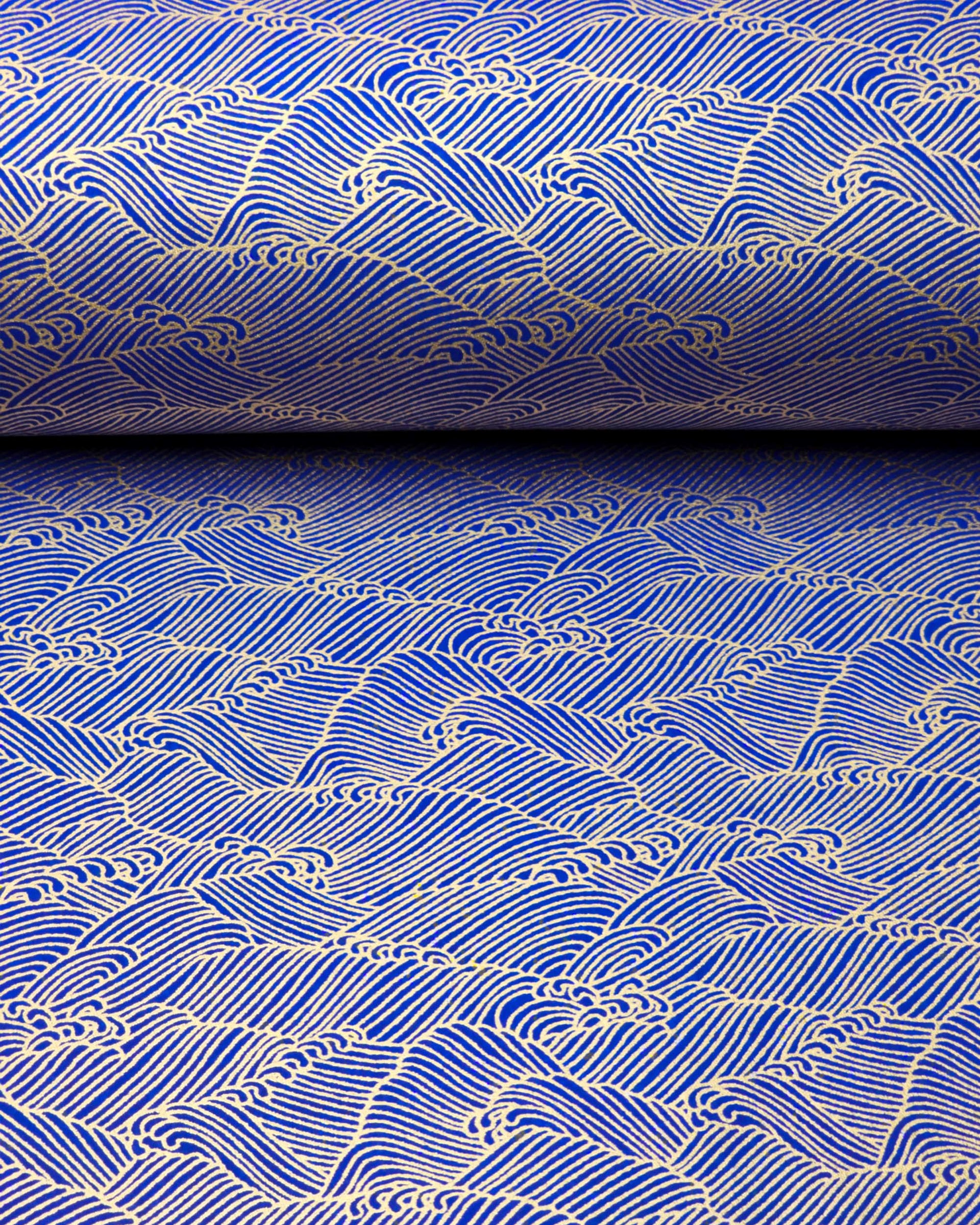 Japanese chiyogami paper featuring small metallic gold waves (aranami) on a dark blue background.