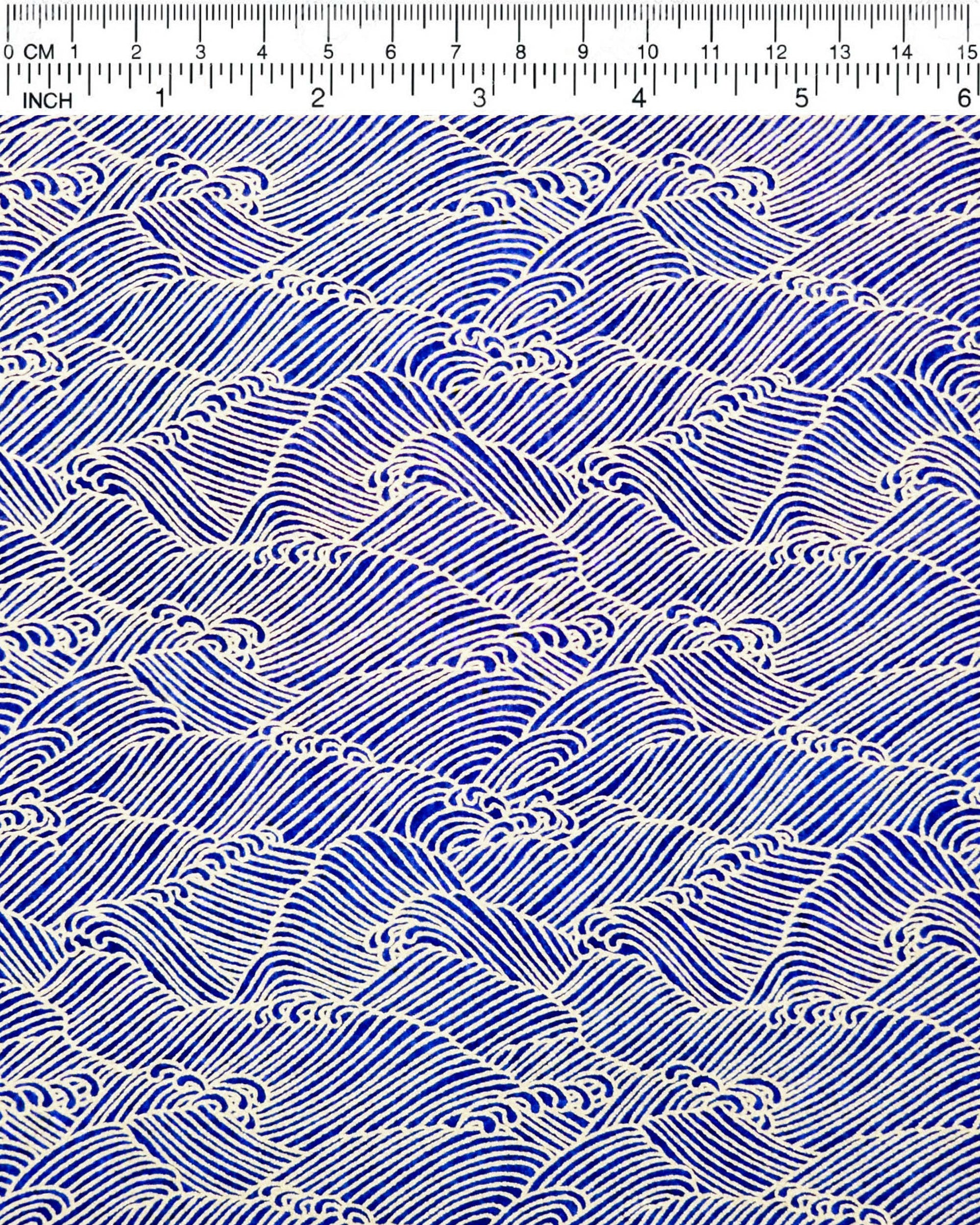 Japanese chiyogami paper featuring small metallic gold waves (aranami) on a dark blue background.