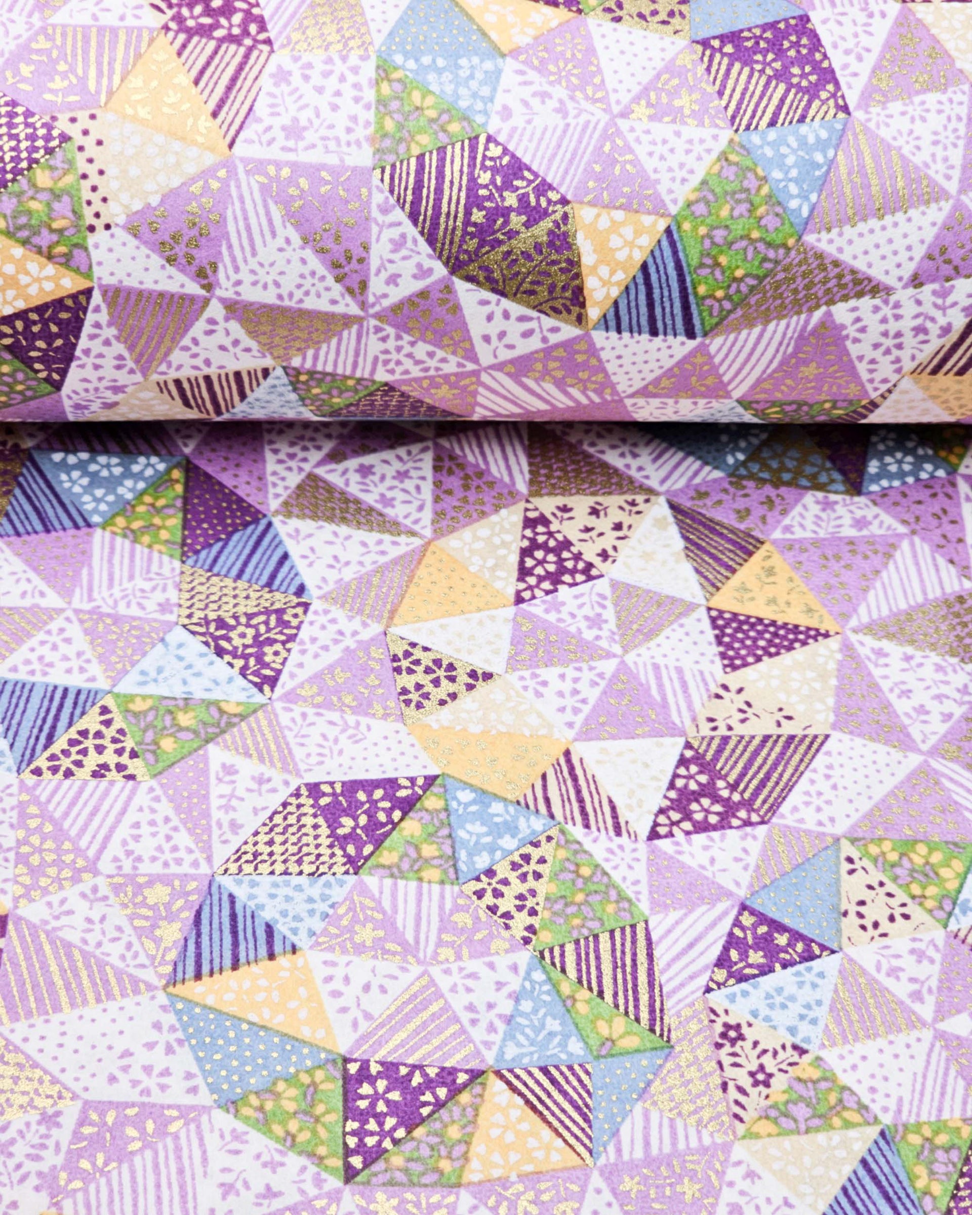 Japanese chiyogami paper featuring purple, yellow, green, and blue triangular patches decorated with assorted traditional Japanese motifs with metallic gold details.