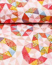 Japanese chiyogami paper featuring pink, yellow, green, and blue triangular patches decorated with assorted traditional Japanese motifs with metallic gold details.