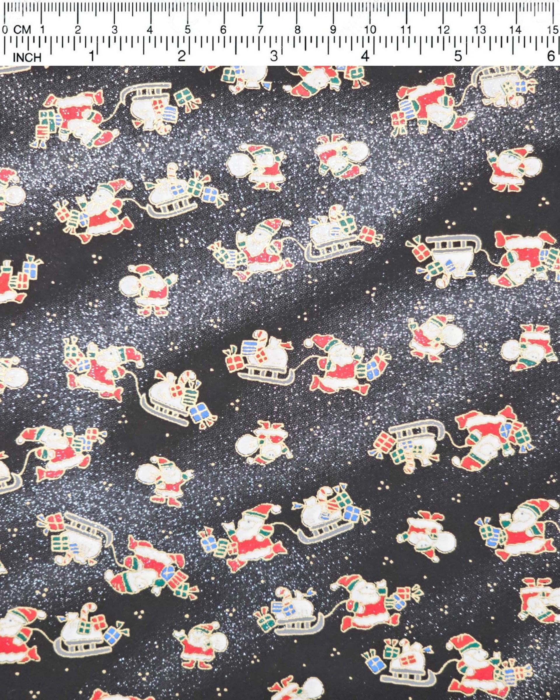 Japanese chiyogami paper featuring Santa and his sleigh on a black and background with metallic gold accents and metallic silver glitter.
