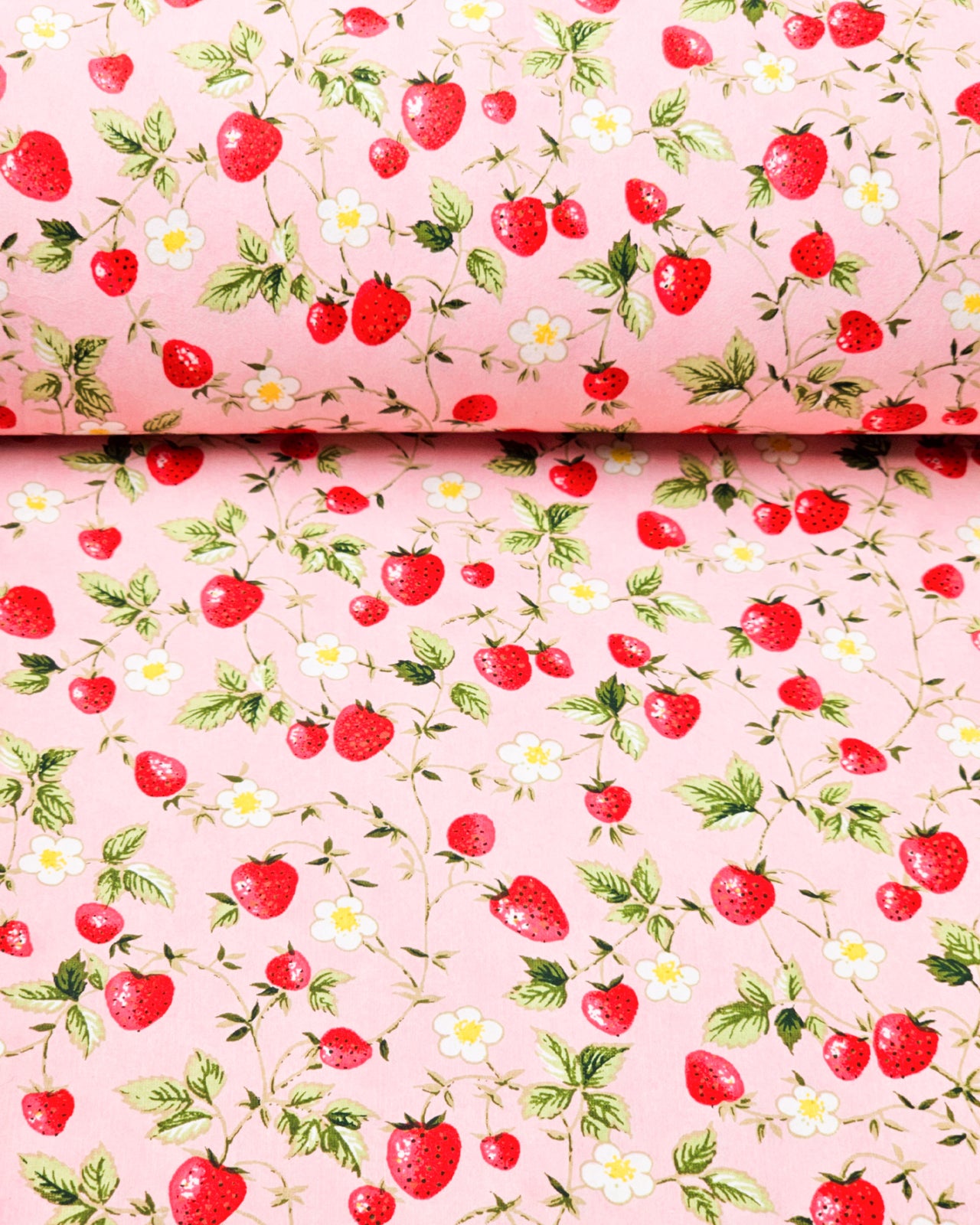 Japanese chiyogami paper featuring red strawberries with green leaves and white flowers with yellow centers on a pink background. 